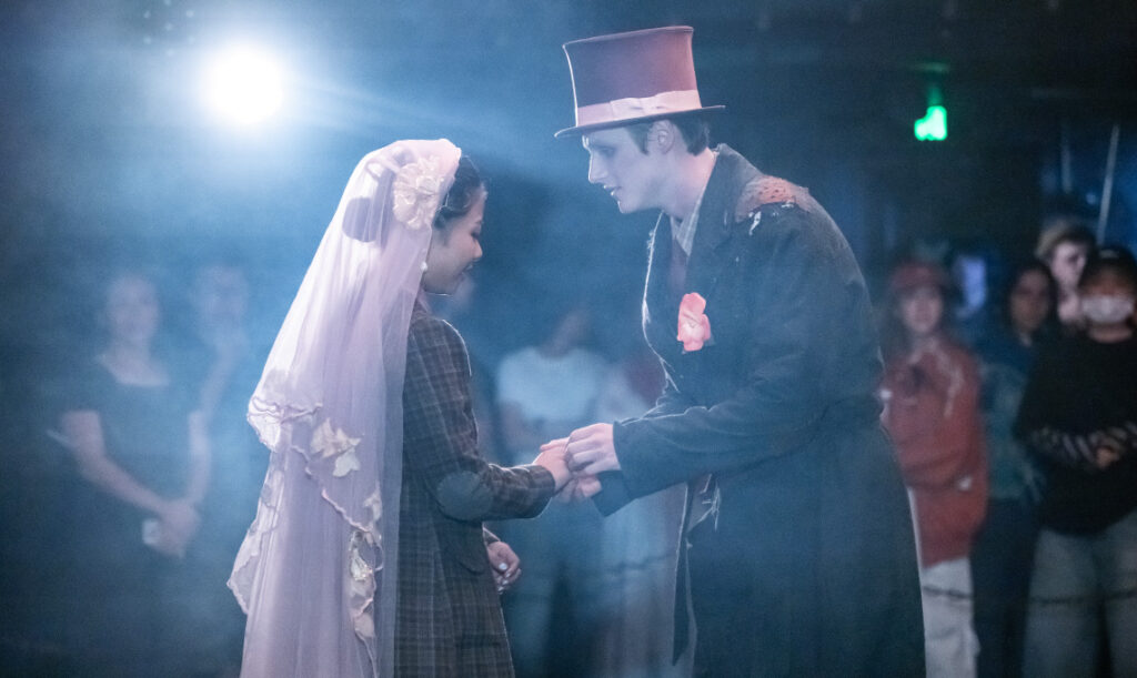 The Deal - Man and women holding hands Image of The Deal production. 1920s style clothing and a misty setting. The women is wearing a veil and man is wearing a top hat; they are holding hands and looking at each other.